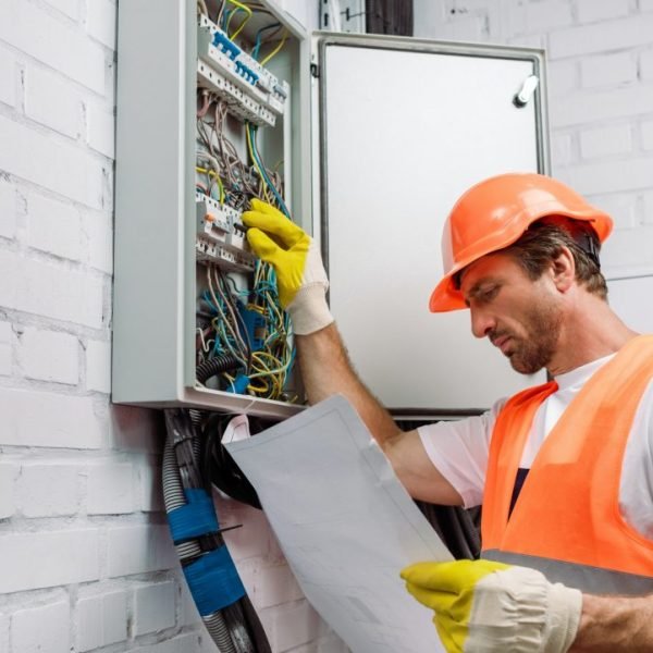 handsome-electrician-in-gloves-looking-at-blueprint-and-fixing-electrical-distribution-box.jpg